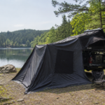 Overland truck with rooftop tent and awning set up beside a Canadian lake in early summer, ready for backcountry camping and vehicle maintenance prep